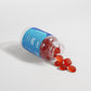 Natural red gummies spilling out of a clear container, highlighting their texture and vibrant color.
